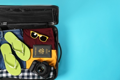 Photo of Open suitcase with traveler's belongings on color background, top view. Space for text