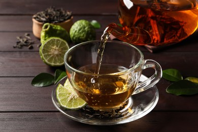 Photo of Pouring bergamot tea into glass cup at wooden table, closeup