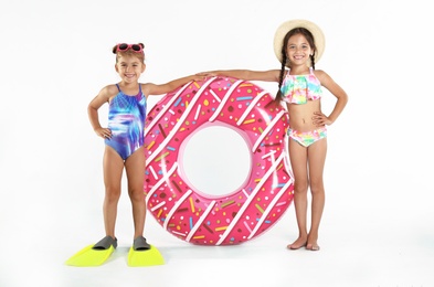 Photo of Cute little children in beachwear with bright inflatable ring on white background