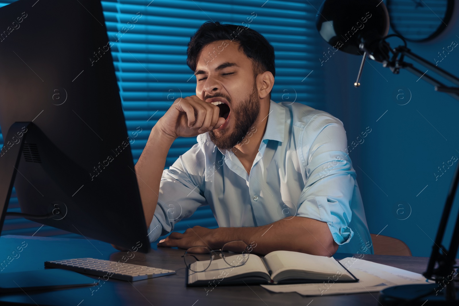 Photo of Tired young man working late in office