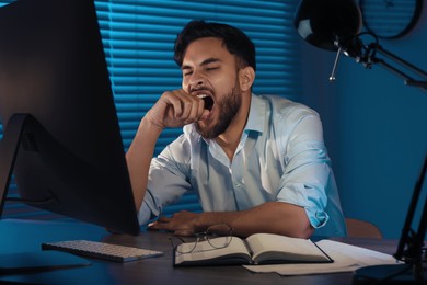 Photo of Tired young man working late in office