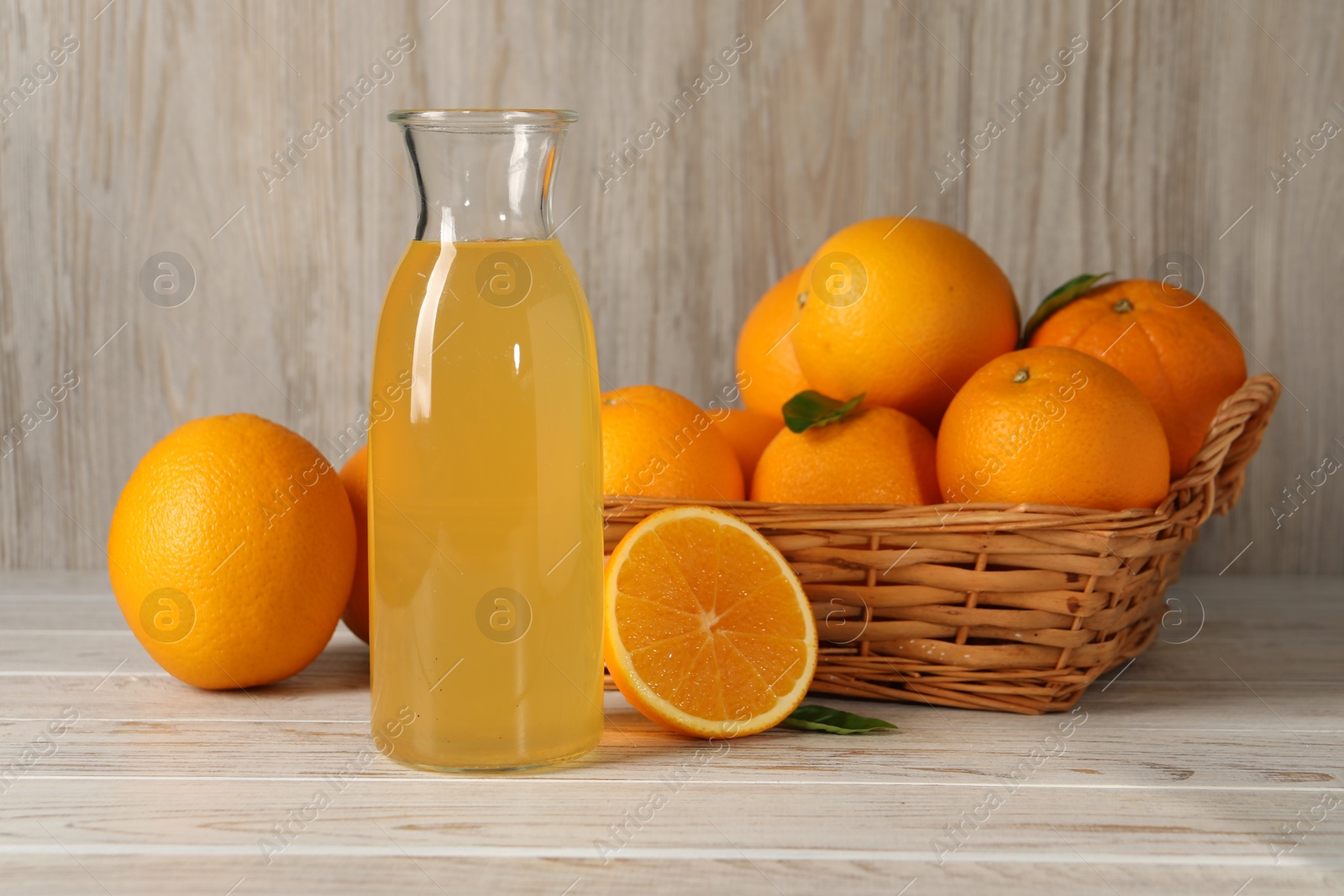 Photo of Many ripe oranges and fresh juice on light wooden table