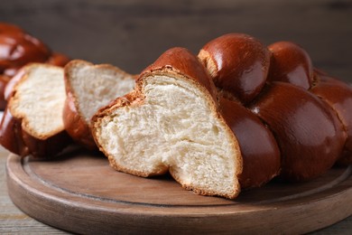 Photo of Cut homemade braided bread on wooden table, closeup. Traditional Shabbat challah