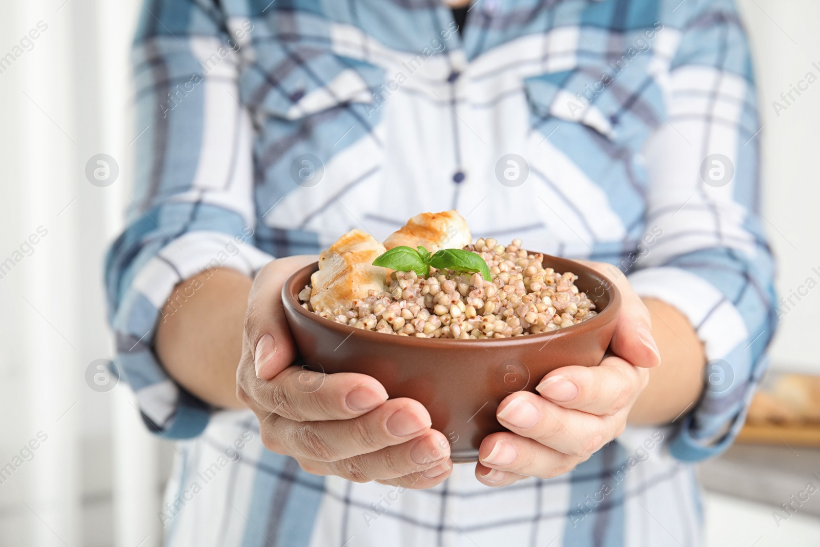 Photo of Woman holding bowl with tasty buckwheat porridge and meat, closeup