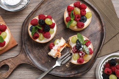 Delicious tartlets with berries on wooden table, flat lay