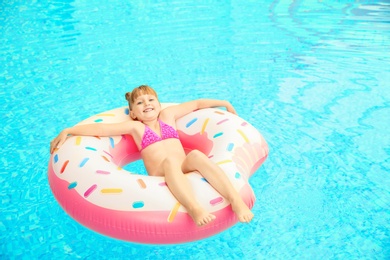 Happy girl relaxing on inflatable ring in swimming pool