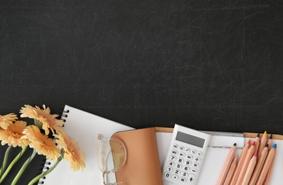 Photo of Different school stationery and beautiful flowers on blackboard, flat lay with space for text. Happy Teacher's Day