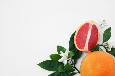 Photo of Fresh ripe grapefruits and green leaves on white background, flat lay. Space for text