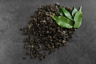 Photo of Heap of dried green tea leaves on grey table, top view