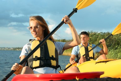 Photo of Couple in life jackets kayaking on river. Summer activity