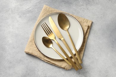 Photo of Stylish cutlery, plate and napkin on light grey table, top view