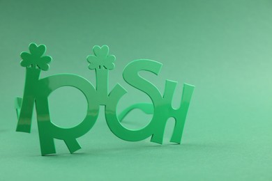 St. Patrick's day. Party glasses with word Irish on green background, closeup