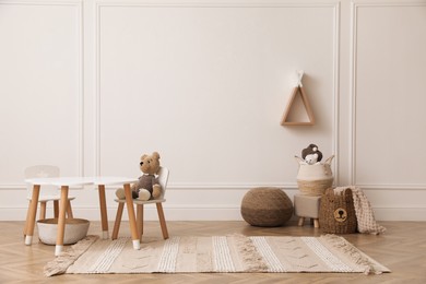 Photo of Cute child room interior with furniture, toys and wigwam shaped shelf on white wall