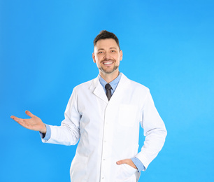 Photo of Happy man in lab coat on light blue background