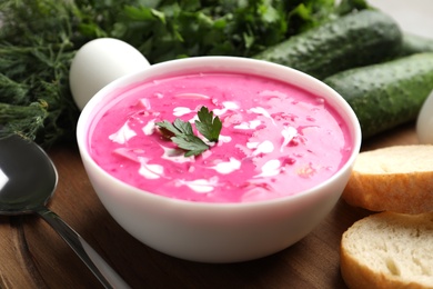 Photo of Delicious cold summer beet soup on wooden board, closeup