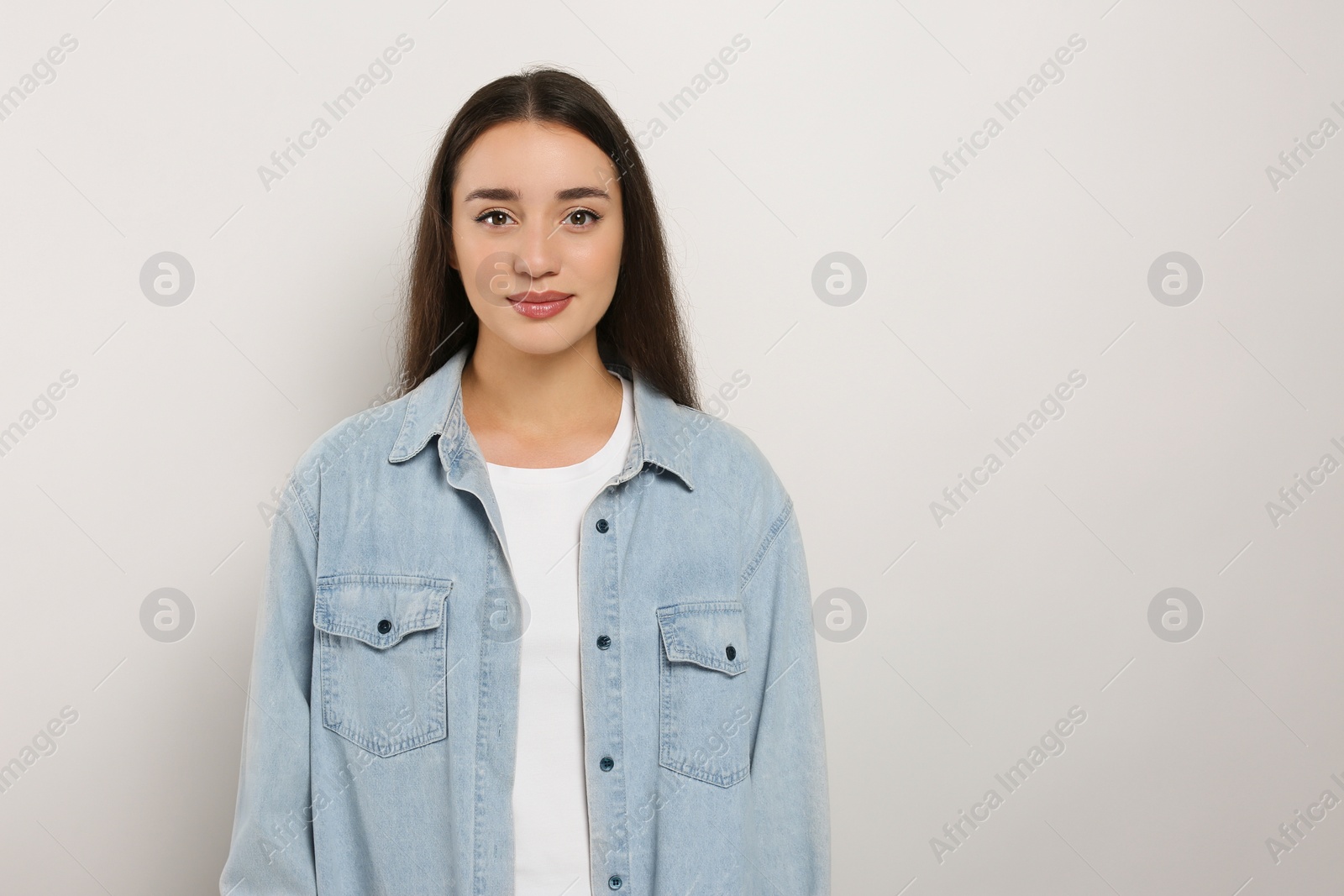 Photo of Portrait of beautiful young woman in jeans jacket on white background. Space for text