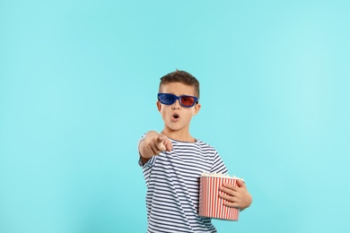 Photo of Emotional boy with 3D glasses and popcorn during cinema show on color background