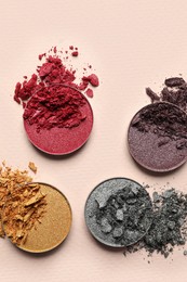 Photo of Different crushed eye shadows on beige background, flat lay