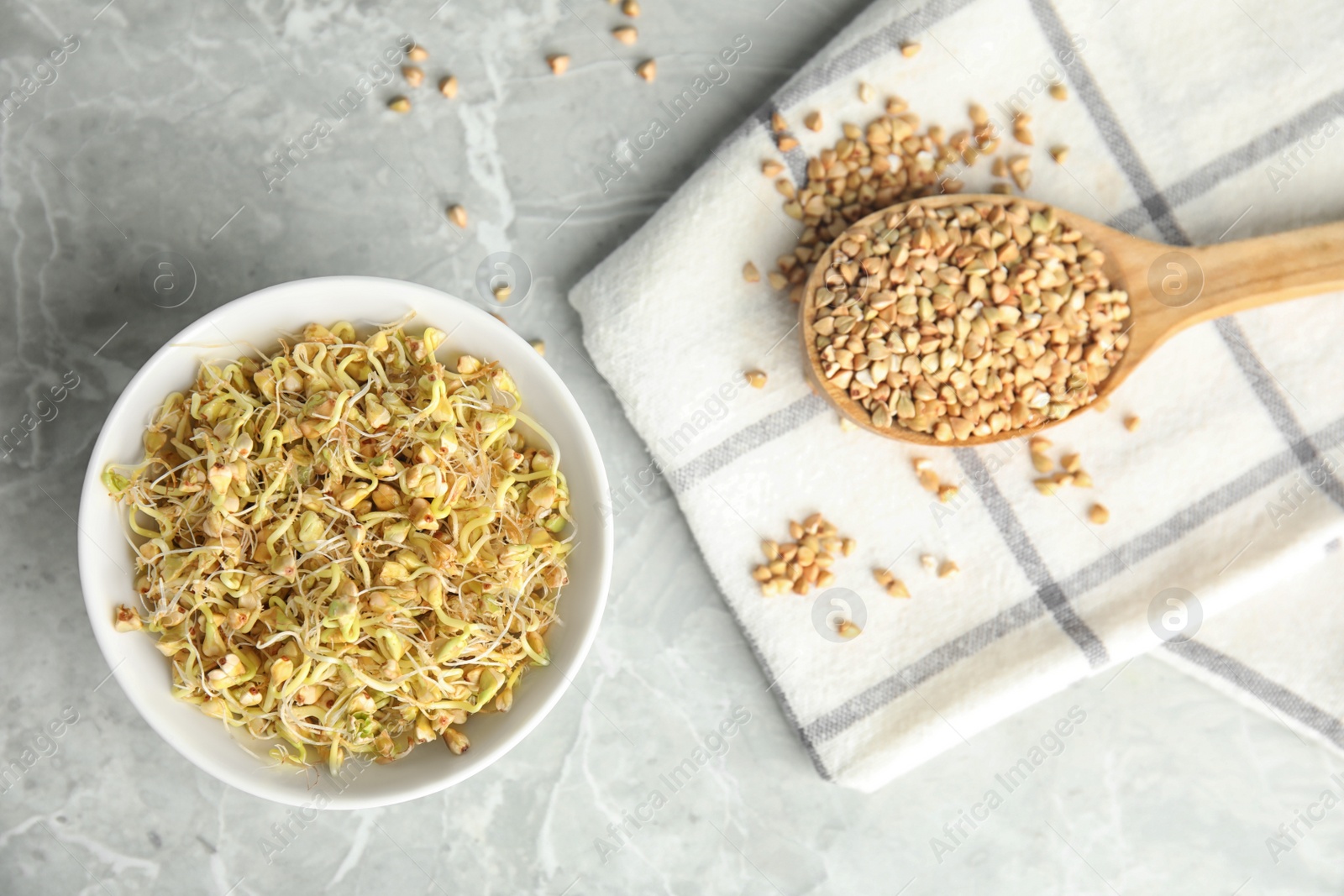 Photo of Bowl of sprouted green buckwheat and spoon with grains on light grey table, flat lay