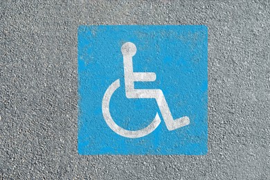 Image of Wheelchair symbol on asphalt road, top view. Disabled parking permit