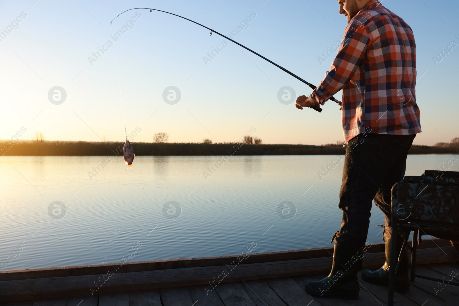 Photo of Fisherman catching fish with rod at riverside, closeup