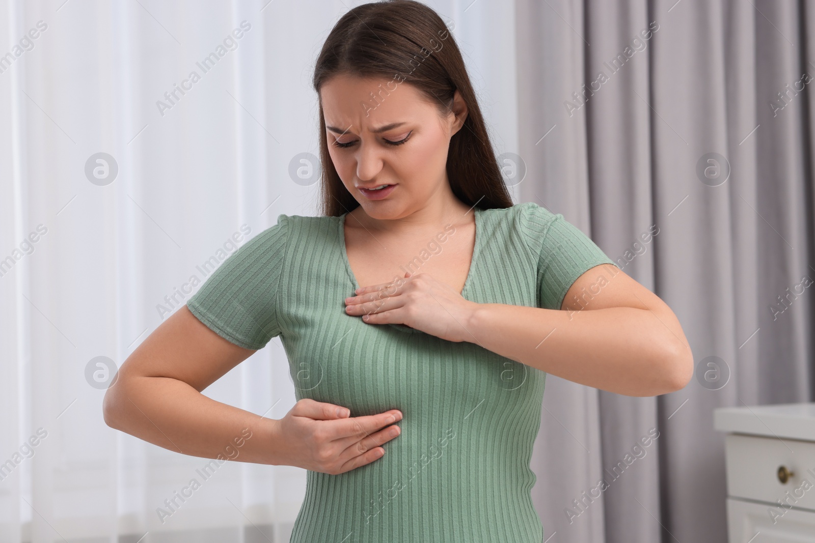 Photo of Mammology. Woman doing breast self-examination at home