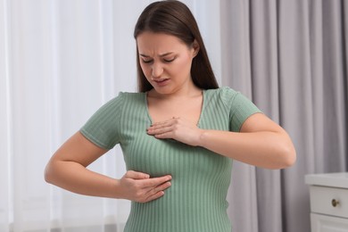 Mammology. Woman doing breast self-examination at home