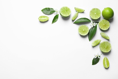 Photo of Frame made of limes, flowers and leaves on white background, top view with space for text. Citrus fruits