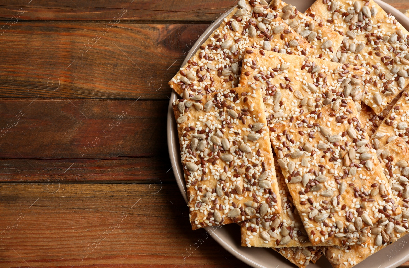 Photo of Delicious crispy crackers on wooden table, top view. Space for text