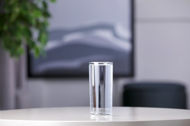 Glass of clean water on white table indoors