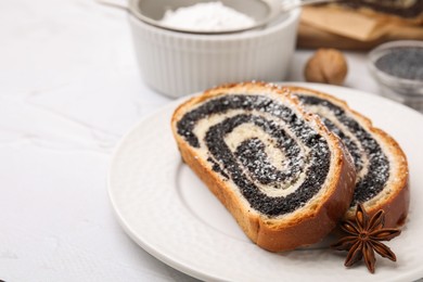 Slices of poppy seed roll and anise star on white table, closeup with space for text. Tasty cake