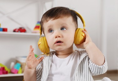 Photo of Cute little boy in headphones listening to music at home