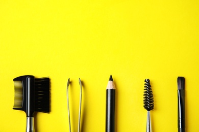 Set of professional eyebrow tools on yellow background, flat lay. Space for text