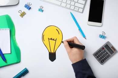 Photo of Woman drawing bulb on white background. Business trainer concept