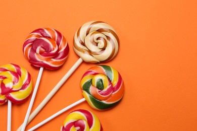 Sweet lollipops on orange background, flat lay. Space for text