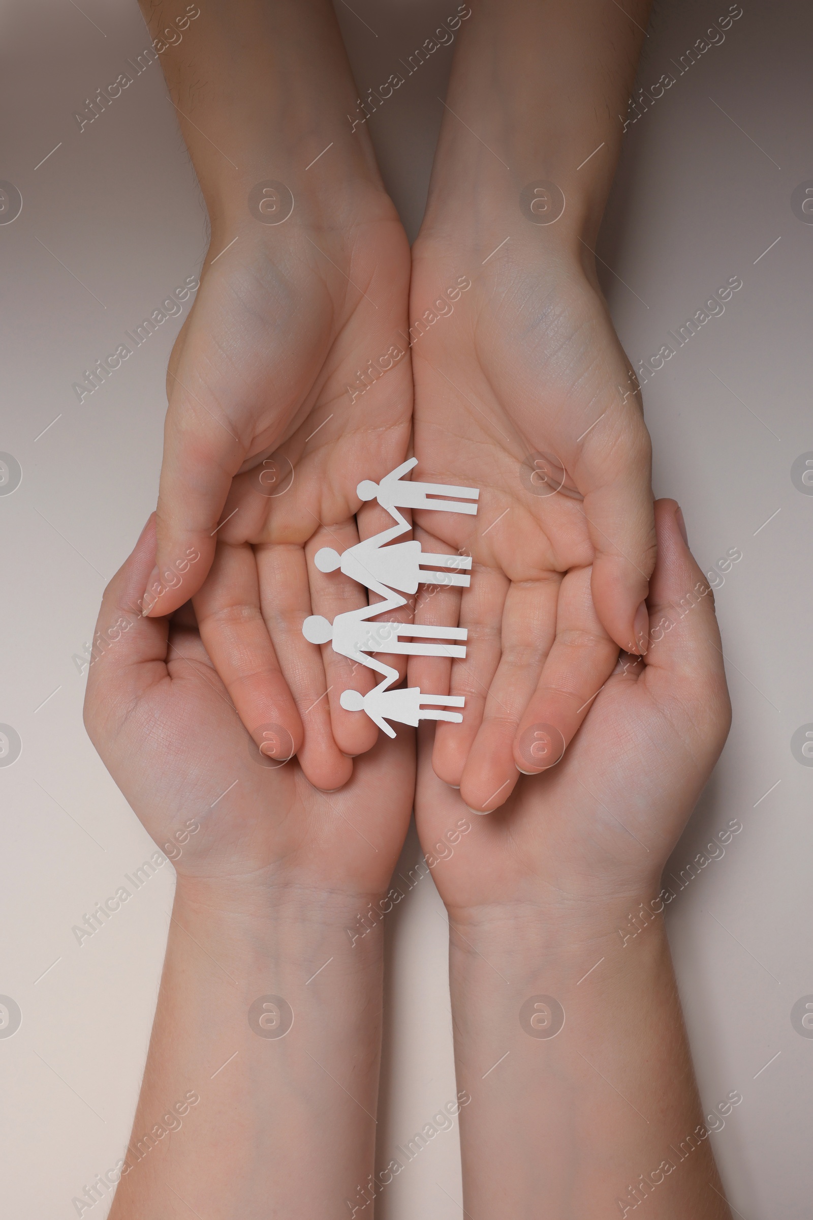 Photo of Couple holding paper family figures on beige background, top view. Insurance concept