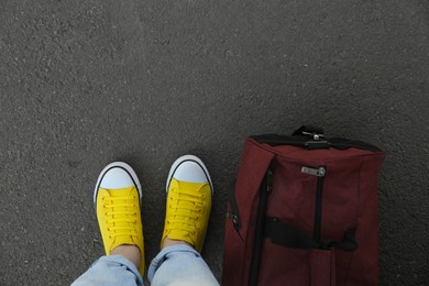 Photo of Woman with bag standing on asphalt, top view. Space for text