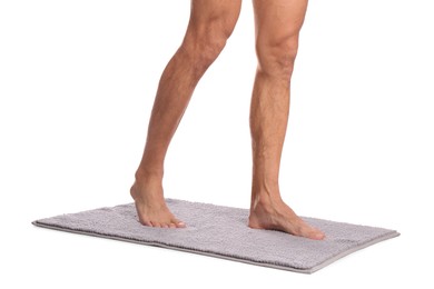 Photo of Man standing on soft grey bath mat against white background, closeup