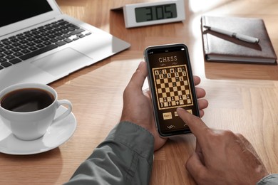 Image of Man playing online chess on smartphone at table, closeup