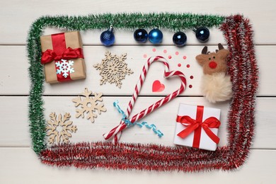 Photo of Bright tinsel and Christmas decor on white wooden background, flat lay