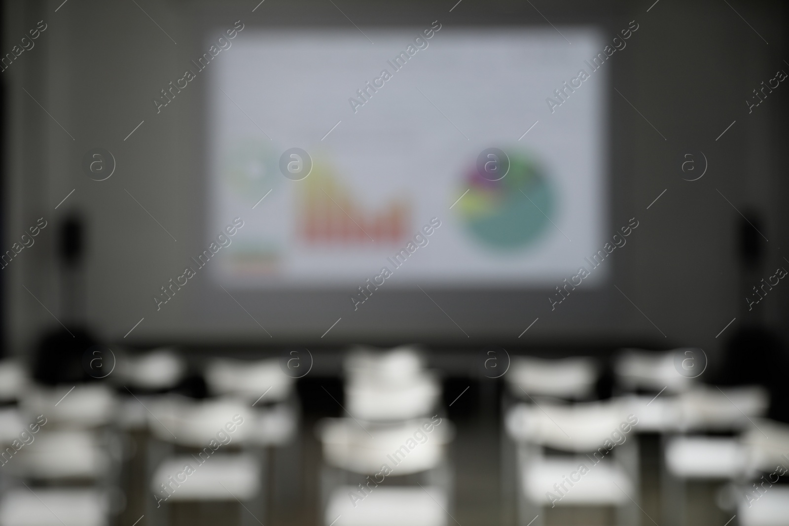 Photo of Blurred view of empty conference room with chairs and projector screen