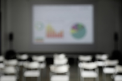 Photo of Blurred view of empty conference room with chairs and projector screen