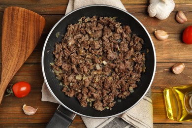 Fried minced meat with onion served on wooden table, flat lay