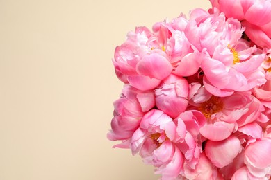 Bunch of beautiful peonies on beige background, top view. Space for text