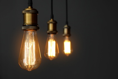 Photo of Pendant lamps with light bulbs on grey background. Space for text