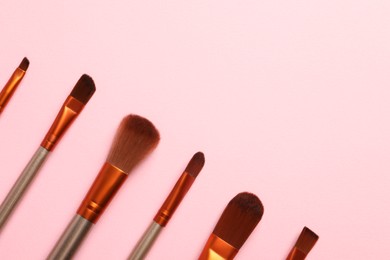 Photo of Set of makeup brushes on pink background, flat lay. Space for text