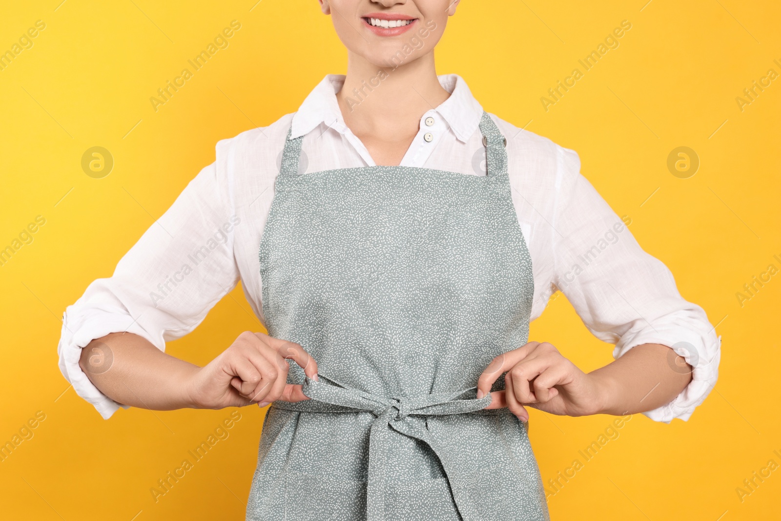 Photo of Woman in clean apron with pattern on orange background, closeup