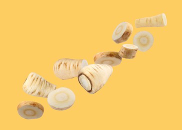 Image of Pieces of parsnip root falling on pale orange background