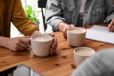 Women with cups of coffee at table in cafe, closeup