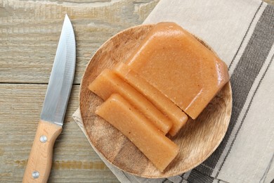 Tasty sweet quince paste and knife on wooden table, top view
